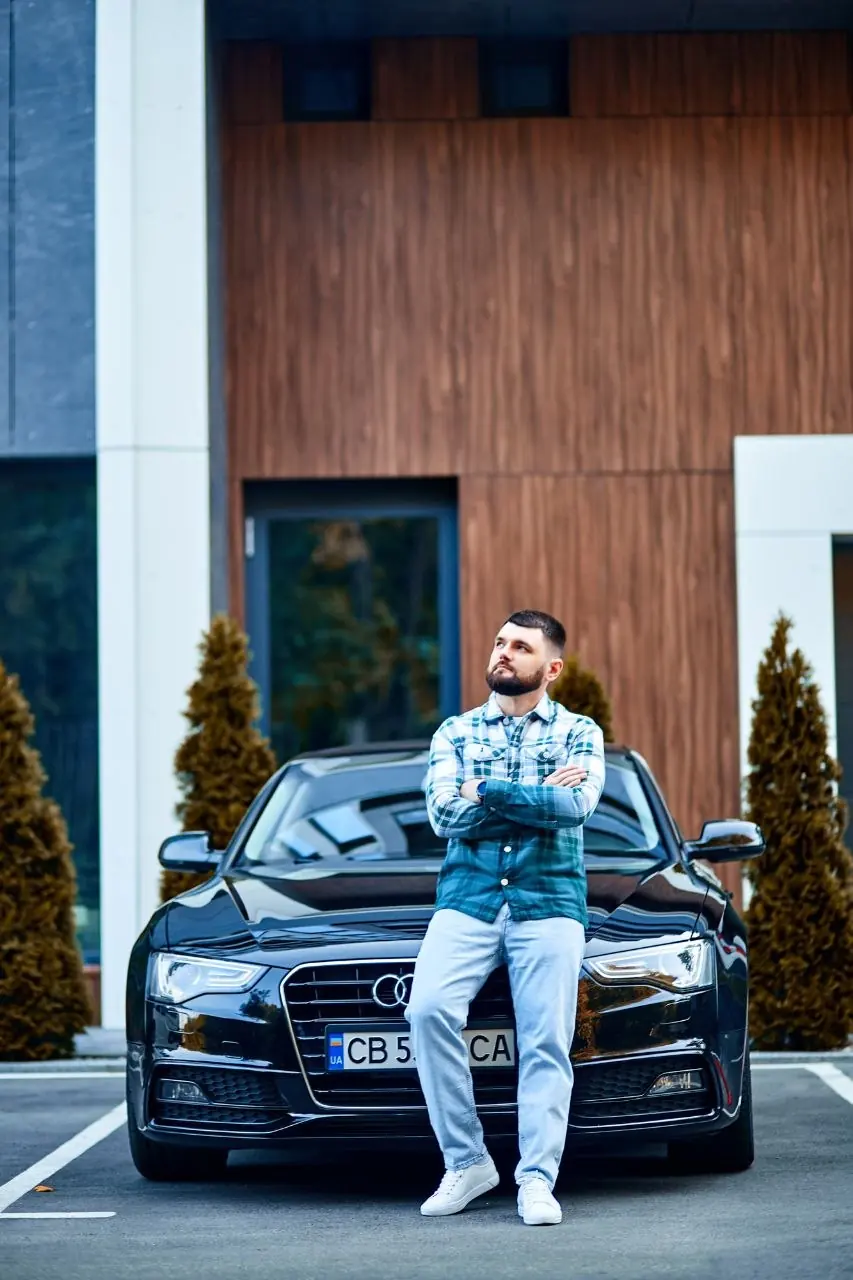 Sergiy Shram standing in front of a black car
